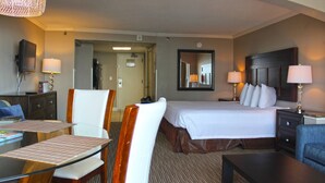 A hotel room with a bed, a desk with a chair, a TV, and a mirror. - Oceanview Villa With NEW Furniture! (Myrtle Beach)