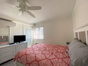 A bedroom with a bed, dresser, TV, ceiling fan, and window with blinds. - Great Views of the Beach! (Myrtle Beach)