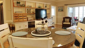 Un coin repas comprenant une table ronde, des chaises, un téléviseur et une bibliothèque.