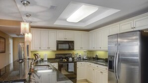 Una cocina moderna con armarios blancos, electrodomésticos de acero inoxidable y una isla grande con fregadero.