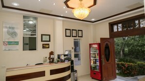 A reception area with a curved reception desk, a red Coca-Cola refrigerator, beige sofas, and a chandelier.