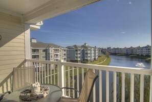 A balcony with a glass table and chairs, overlooking a river and a row of apartment buildings. - Just an 8 Minute Drive to Myrtle Beach Sands... (Myrtle Beach)