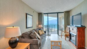 Habitació d'hotel amb sofà, taula, televisió i balcó amb vista a l'oceà.