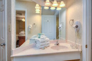 A bathroom with a large mirror, a sink, and a hairdryer mounted on the wall.