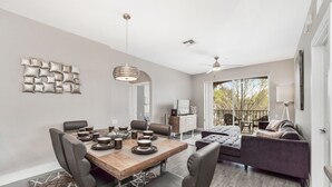 Een moderne woonkamer met een eethoek, een bank en een plafondventilator.