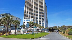 Un hotel alt amb un disseny modern, que destaca per un gran nombre de balcons i un cartell ben visible.