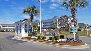 A hotel entrance with a flag, palm trees, and a sign indicating parking by permit only. - Great Views of the Pool and Grilling Area! (Myrtle Beach)