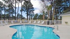 A swimming pool with a curved edge, surrounded by a white fence and lounge chairs. - Great Views of the Pool and Grilling Area! (Myrtle Beach)
