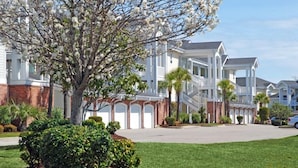 A multi-story residential building with a central courtyard, surrounded by well-maintained lawns and mature trees. - Peacefulmyrtlewood Villa Right in the Heart of MB (Myrtle Beach)