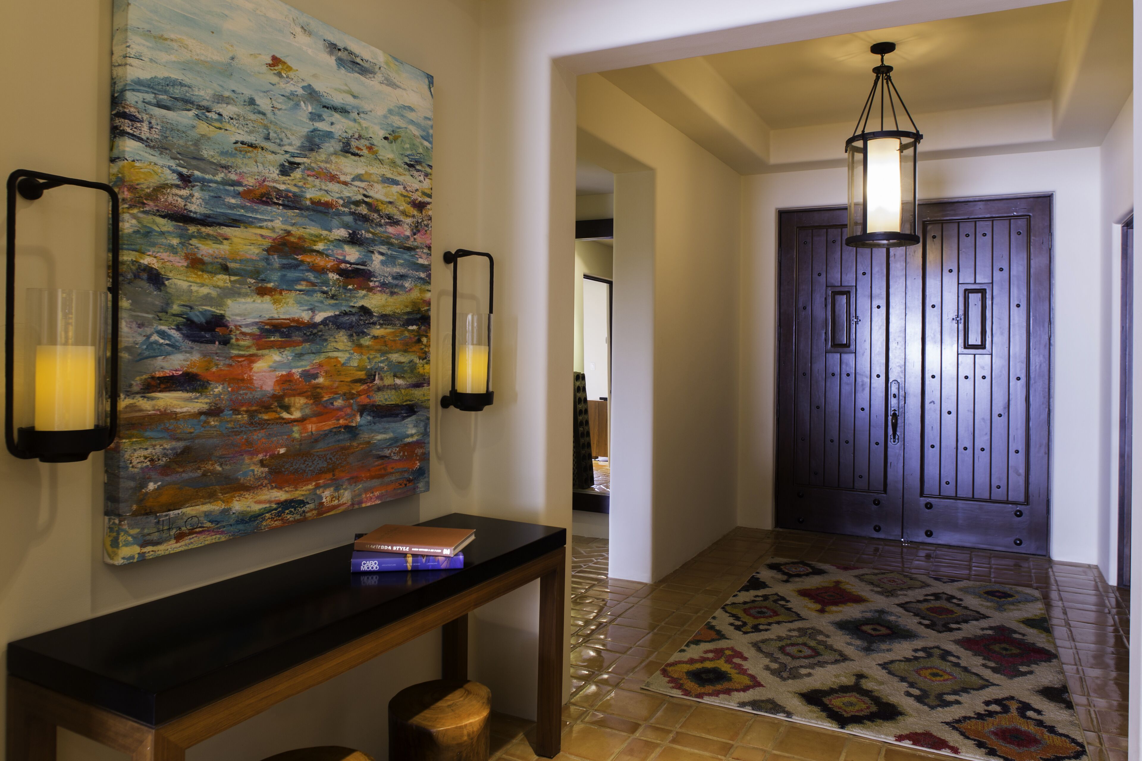 Un couloir doté d’un plancher en bois, d’un tapis à motifs, d’un tableau, d’une console et d’une porte à deux battants.