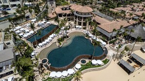 An aerial view of a resort with a large central pool, multiple guest rooms, and a beach area. - Hacienda Beach Club Oceanview 4BR home– Prime Cabo Location (Cabo San Lucas,)