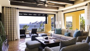 A spacious balcony with a view of the sea and mountains, furnished with a sofa, chairs, and a coffee table. - Hacienda Beach Club Oceanview 4BR home– Prime Cabo Location (Cabo San Lucas,)