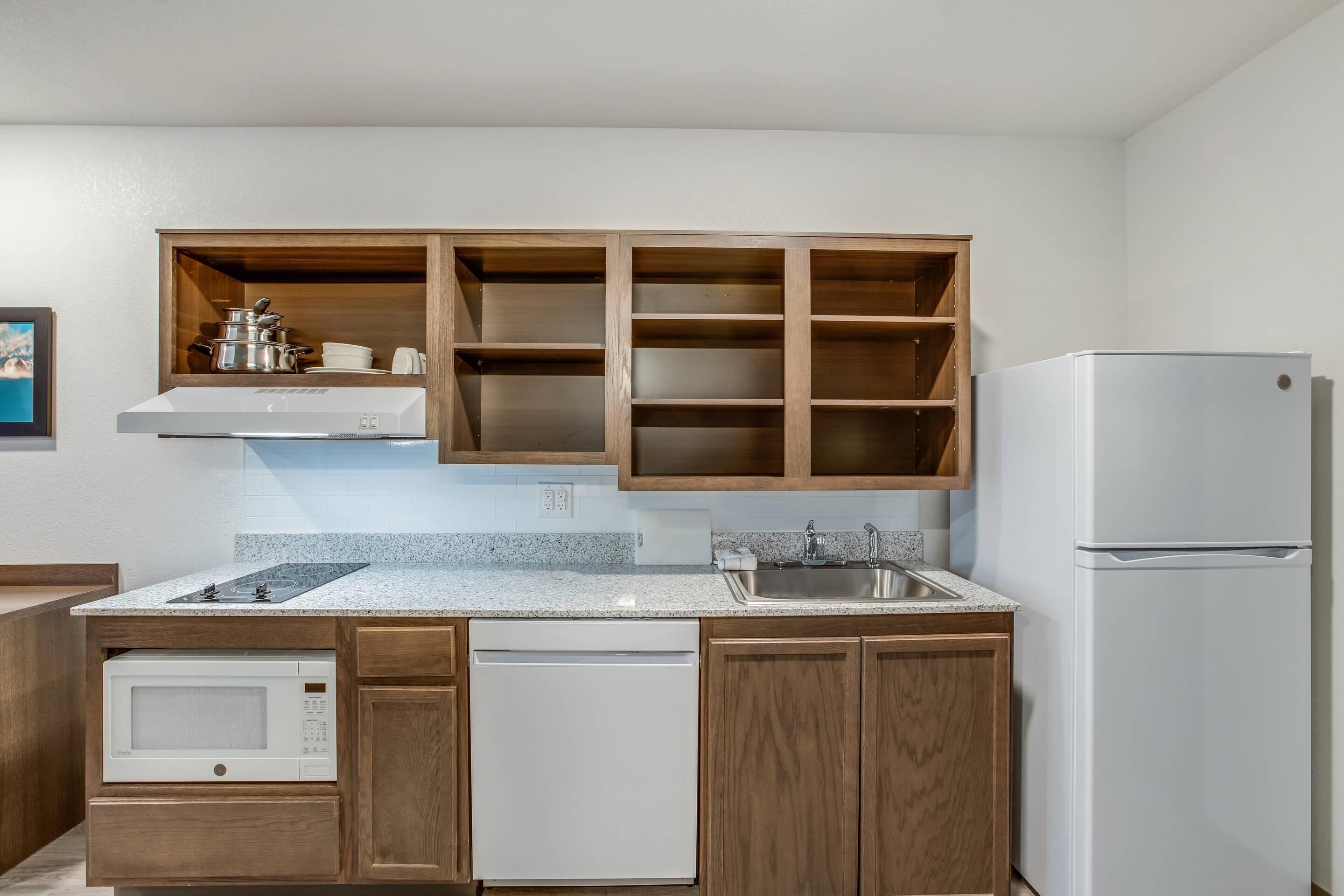 A kitchen with wooden cabinets, a white refrigerator, a microwave, and a dishwasher.
