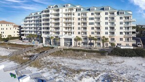 A multi-story hotel with balconies, a beach view, and a parking area.