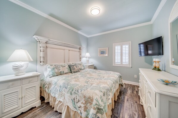 A bedroom with a bed, nightstands, a dresser, a television, and a window with shutters. - 2-Story Penthouse at The Inn at Crystal Beach! Beachfront Designer 5BR/4BA. Sleeps 14 (Destin)
