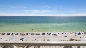 A beach with clear turquoise water, people swimming, and umbrellas on the sand.