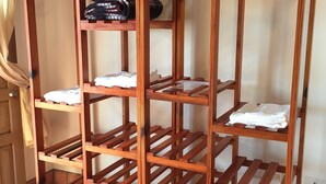 Ein mehrstufiger Wäscheständer aus Holz mit Ablagen und Kleiderbügeln auf einem gefliesten Boden.