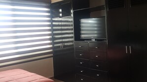 A bedroom with two beds, a wardrobe, and a television.