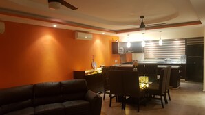 A modern kitchen with a dining area, featuring a sofa, chairs, and a ceiling fan.