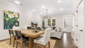 Ein modernes Wohnzimmer mit einem Holzespeisetisch, weißen Sofas und einem großen Blumenbild.