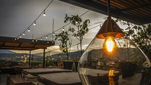 Un área de estar al aire libre con luces colgantes y una vista despejada del paisaje.