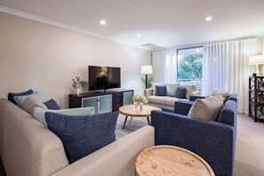 Un salon moderne comprenant un canapé, une table basse et un téléviseur à écran plat.