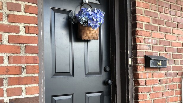Eine schwarze Tür mit einem Korb blauer Blumen.