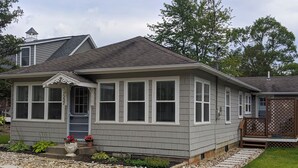 A single-story house with a grey siding exterior, a front porch with a small porch area, and a visible chimney. - Remodeled 3 bedroom - perfect location for beach trips and beautiful sunsets (south haven)
