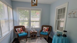 A room with two wicker chairs with blue cushions, a small table with a decorative item, and a blue tablecloth. - Remodeled 3 bedroom - perfect location for beach trips and beautiful sunsets (south haven)