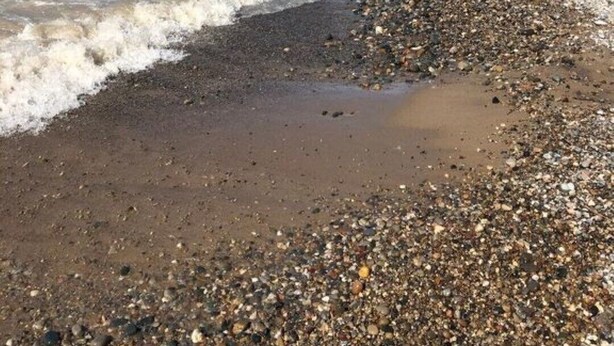 A pebbly beach with waves lapping at the shore, a clear sky, and a distant shoreline. - Remodeled 3 bedroom - perfect location for beach trips and beautiful sunsets (south haven)
