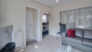 A modern living room with a grey sofa, a remote control, and a glass coffee table. - Newark House - 2 Bedroom Apartment (Maidenhall)