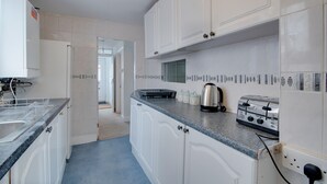 A kitchen with white cabinets, a blue countertop, a toaster, and a kettle. - Newark House - 2 Bedroom Apartment (Maidenhall)