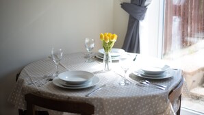 A dining table set with plates, cutlery, and a vase of yellow flowers. - Newark House - 2 Bedroom Apartment (Maidenhall)
