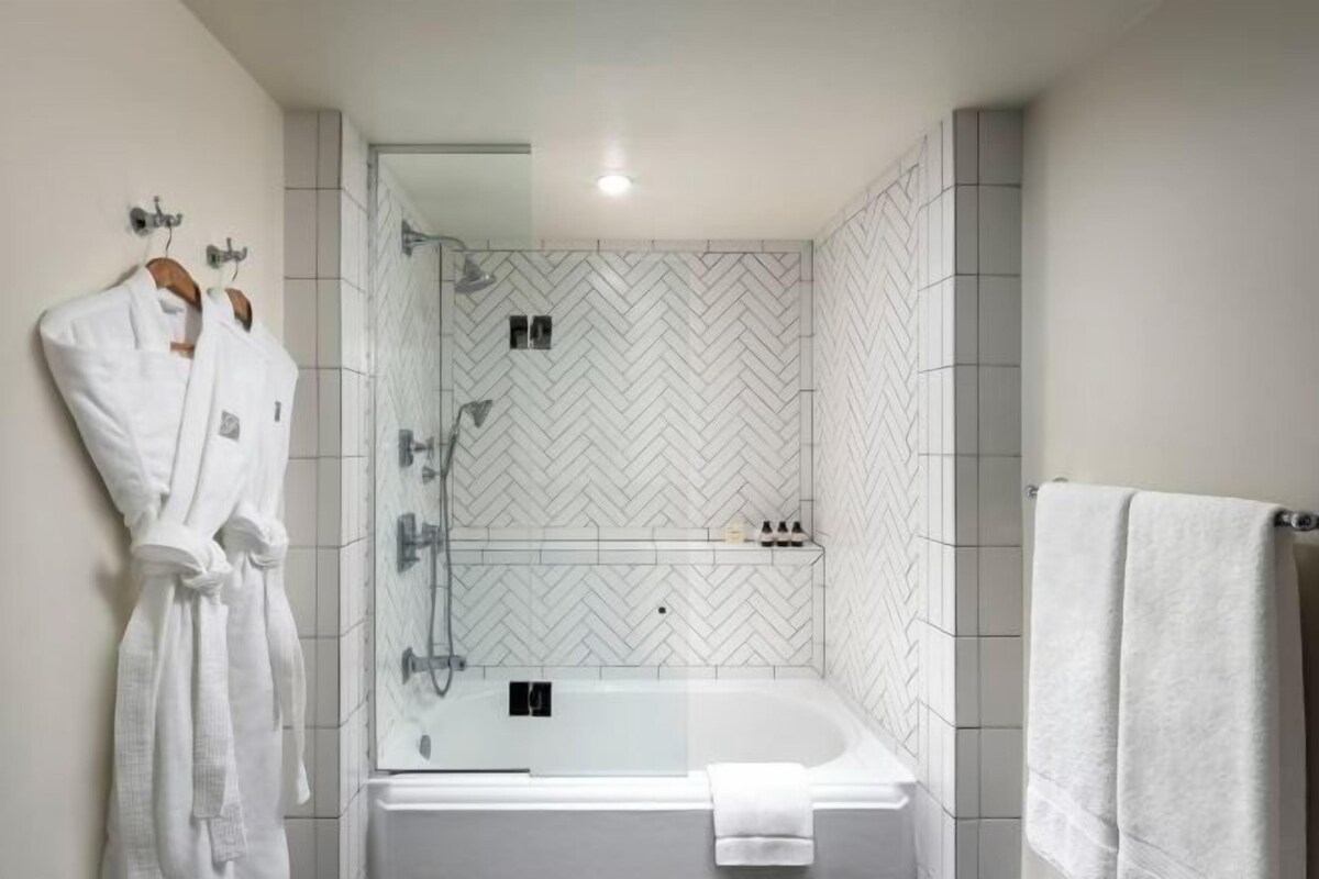 A modern bathroom with a large bathtub, a shower area, and a towel rack.