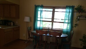 A dining area with a table and chairs, a lamp, and a window with curtains. - Awesome house in Waterhill Neighborhood (Ann Arbor)