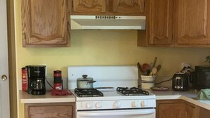 A kitchen with wooden cabinets, a white stove, and a coffee maker on the counter. - Awesome house in Waterhill Neighborhood (Ann Arbor)