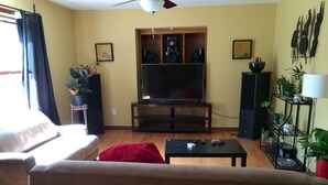 A living room with a sofa, a coffee table, a TV, and a speaker system. - Awesome house in Waterhill Neighborhood (Ann Arbor)