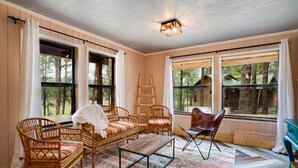 Una habitación acogedora con muebles de mimbre, ventanas amplias y una escalera.