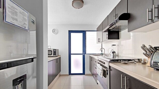 A modern kitchen with stainless steel appliances, a built-in oven, and a microwave. - +MS +Espectacular Suite +Alberca Áreas Verdes +9A (Santiago de Querétaro)