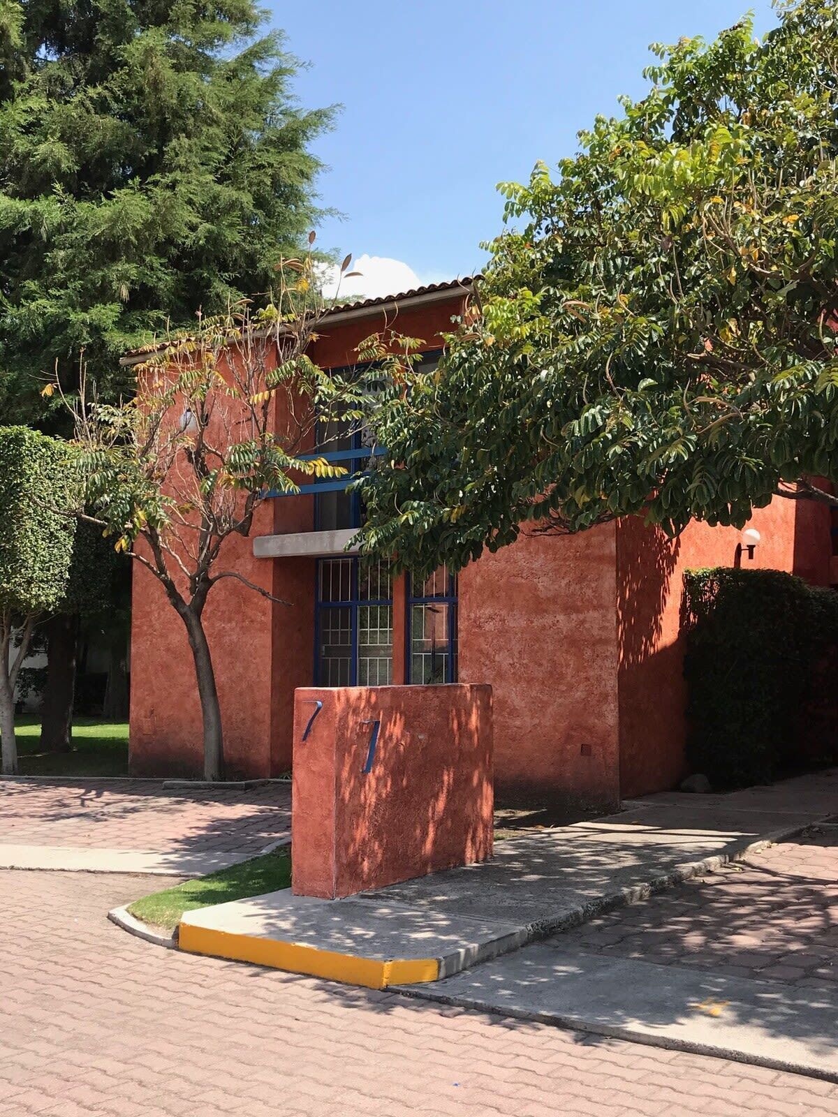 A building with a red brick exterior, a blue-framed window, and a yellow curb.