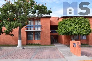 A building with a brick facade, a tree in front, and a sign with the number 792.