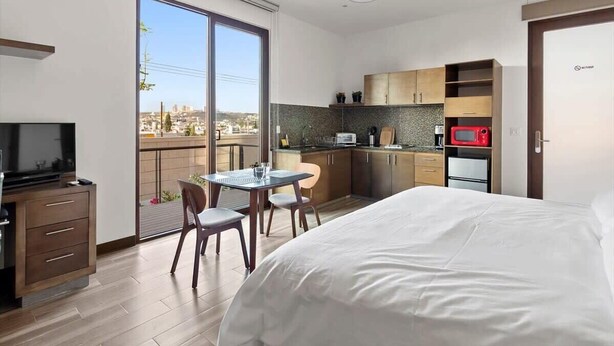 Et moderne hotelværelse med balkon, spiseplads og tekøkken.