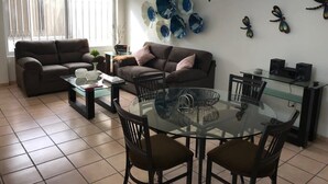 A living room with a sofa, coffee table, dining table, chairs, and decorative wall art. - +MS +Suite Perfecta +Centro +Av Zaragoza +S5 (Santiago de Querétaro)