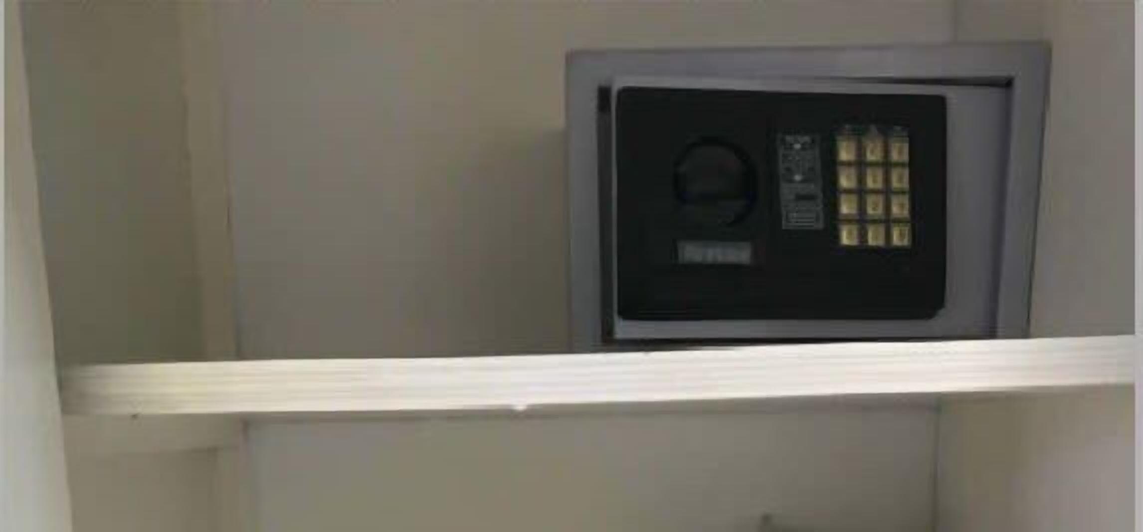 Un coffre-fort sécurisé dans une pièce avec une étagère blanche.