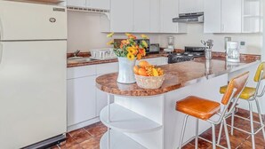 A modern kitchen with white cabinets, a marble countertop, and a central island with stools.