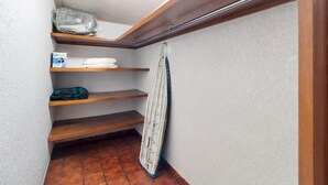 A small, enclosed storage area with wooden shelves, a tiled floor, and a ceiling with a wooden beam.