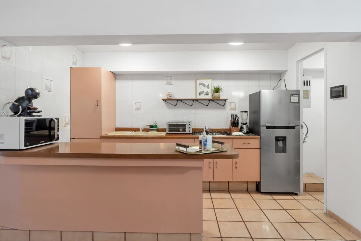 A modern kitchen with white cabinets, a stainless steel refrigerator, a microwave, and a toaster.
