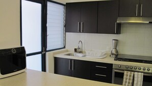 A modern kitchen with black cabinets, a stainless steel sink, a built-in oven, and a microwave. - +MS +Espectacular Suite +Alberca Áreas Verdes +24C (Santiago de Querétaro)