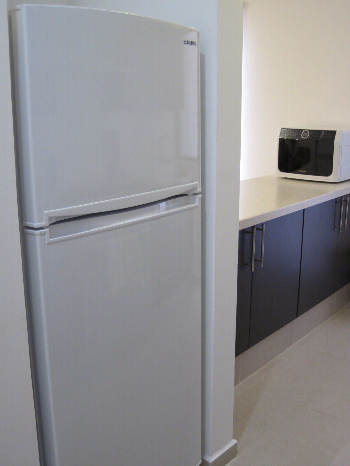 A kitchen with a white refrigerator, a microwave, and dark cabinets.