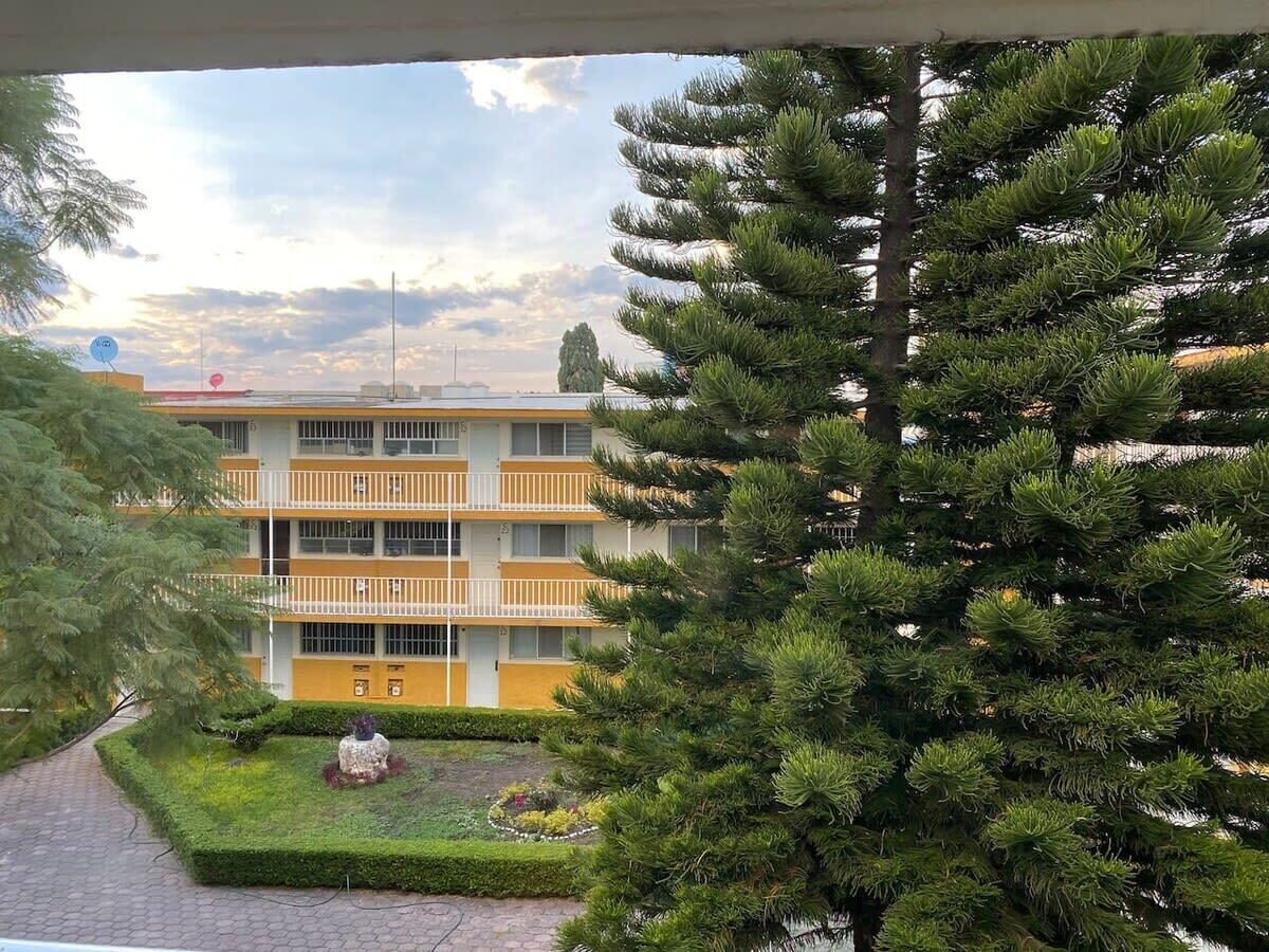 A multi-story building with balconies, a paved pathway, and a well-maintained garden area.